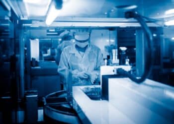 Technicien en laboratoire ajustant des équipements, atmosphère bleutée.