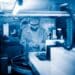 Technicien en laboratoire ajustant des équipements, atmosphère bleutée.