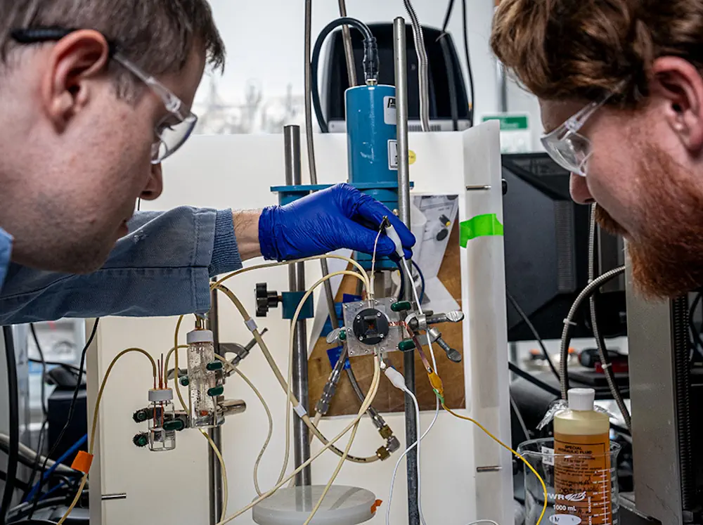 Walter Drisdell (de gauche à droite) et Aidan Coffey, de la division des sciences chimiques du Berkeley Lab, au centre de recherche LiSA du Berkeley Lab, ajustent une pompe qui fait circuler le liquide dans la cellule électrochimique