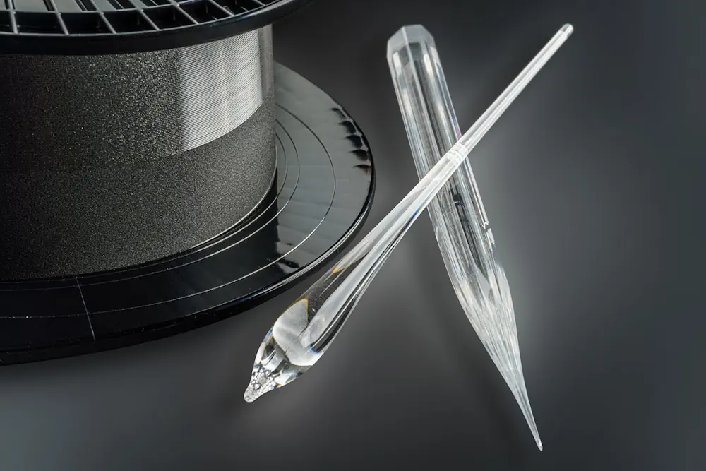 Préforme de fibre octogonale, paraisons de verre au début du processus d'étirage de la fibre et fibre laser active sur le rouleau porteur.