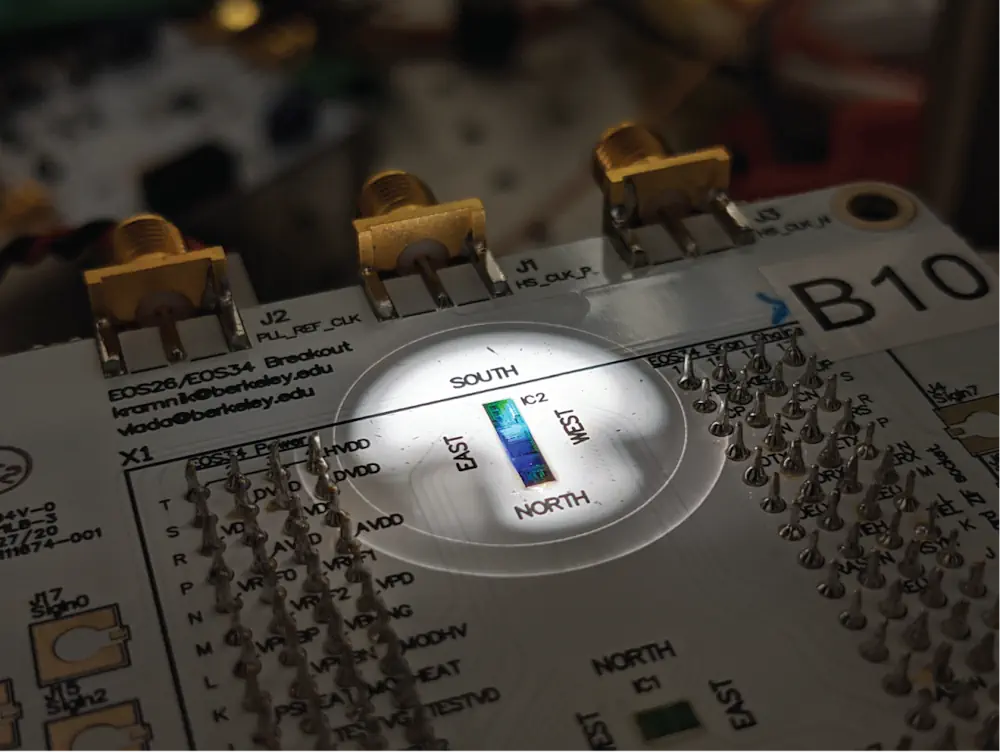 Une carte de circuit imprimé contenant la puce est placée sous le microscope dans une station de sondage au cours d'une expérience. Cette puce en silicium, la première du genre, combine à la fois des composants quantiques générateurs de lumière (photonique) et des circuits de contrôle électronique classiques, le tout sur une surface d'à peine un millimètre sur un millimètre.