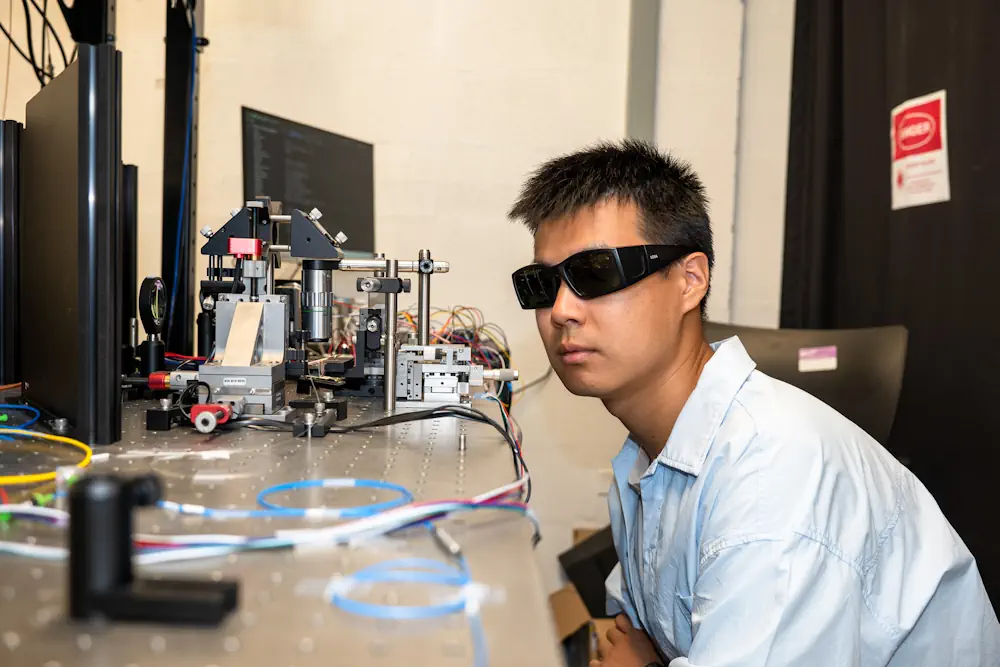 Yichi Zhang, doctorant en science et ingénierie des matériaux, inspecte la source du signal quantique