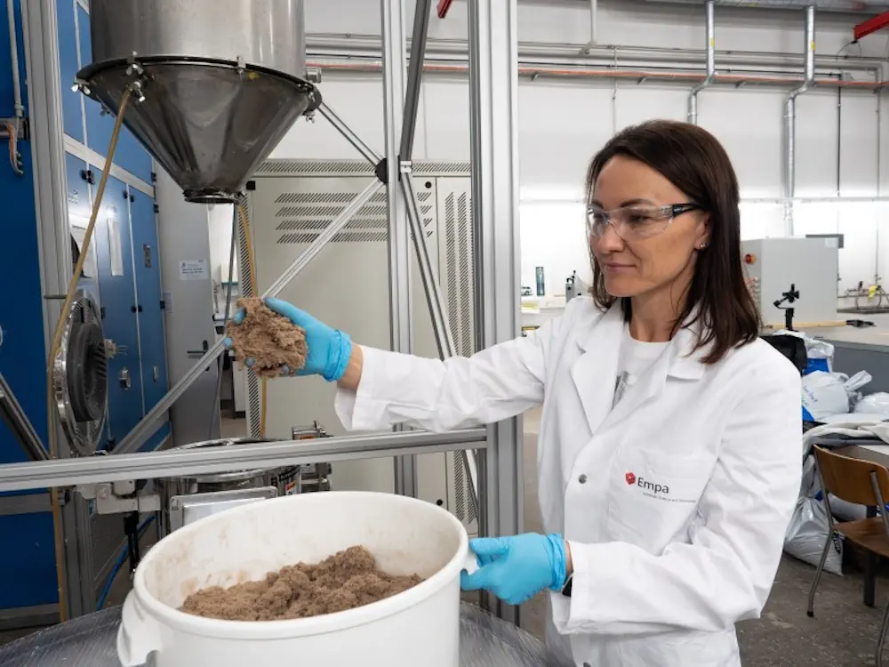 Yuliia Dudnyk, chercheuse à l'Empa, avec la lignocellulose floconneuse, matière première du circuit imprimé.