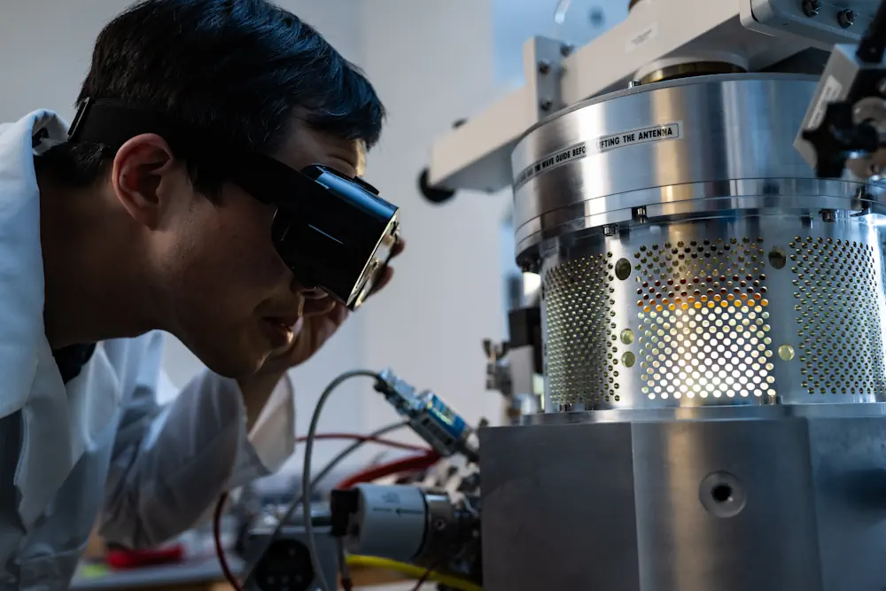 Xiang Zhang avec l'installation de dépôt chimique en phase vapeur par plasma micro-ondes. (Photo de Jeff Fitlow/Université Rice)