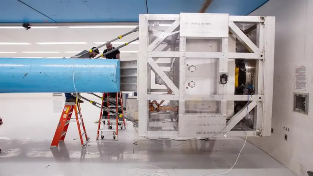 Toby Gomez, à gauche, et Jason King travaillent sur les connexions des capteurs tandis que le rover VIPER est suspendu dans une cage à l'extrémité du bras Superfuge au Sandia National Laboratories.