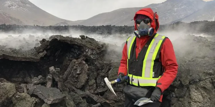 Wearing protective gear against toxic gases, Solange Duhamel stands next to a lava flow during an outing to collect samp