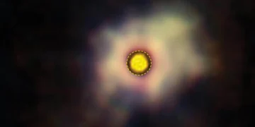 Des nuages de poussière reflètent la lumière stellaire autour de l'étoile R Doradus. Alors qu'elle approche de la fin de sa vie, l'étoile perd ses couches externes, formant autour d'elle des nuages de gaz et de poussière (représentés ici en rose et en jaune).