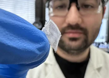 PhD researcher Robert Komljenovic holding the flexible nylon‑film energy‑harvesting device developed at RMIT University.