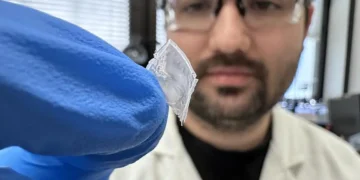 PhD researcher Robert Komljenovic holding the flexible nylon‑film energy‑harvesting device developed at RMIT University.