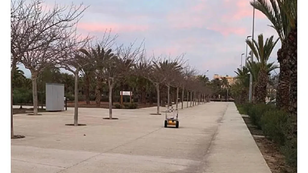 A mobile robot navigates along the UMH Elche campus using the MCL-DLF localization system, which enables accurate positi