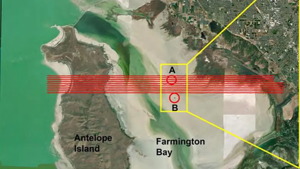 Carte de la zone couverte par le levé électromagnétique aérien superposée au fond de carte ESRI World Imagery. Les tracés des lignes de vol, indiqués en rouge, traversent Antelope Island et Farmington Bay. Les cercles indiquent l'emplacement des monticules de phragmites.