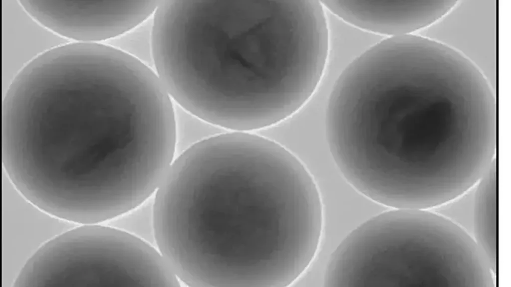 L'un des principaux défis liés à la création d'une encre à base de nanosphères de silicium imprimable résidait dans le fait que, lorsque le solvant sèche, les nanosphères ont tendance à s'agglomérer. L'équipe a surmonté cette difficulté en enrobant chaque cristal (le cœur sombre de chaque bille sur l'image) d'une enveloppe de silice (la partie claire à l'extérieur de chaque bille) dont les propriétés matérielles empêchent la lumière de se réfracter à l'interface avec la résine environnante. En substance, ils ont créé une sorte de « pare-chocs » transparent entre les cristaux.