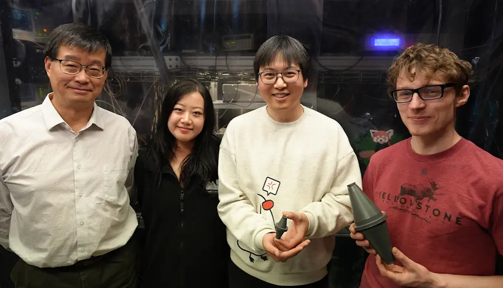 Jun Ye (à gauche), physicien au NIST et au JILA, pose aux côtés des membres de son équipe (de gauche à droite) : Zoey Hu, Dahyeon Lee et Ben Lewis, qui tiennent des répliques d'une cavité laser optique.