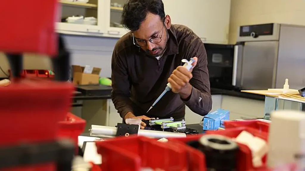 Anupam Pandey, professeur de génie mécanique et aérospatial, règle un banc d'essai pour surfaces souples dans son laboratoire de l'université de Syracuse, où son équipe étudie comment des plis microscopiques peuvent contrôler le mouvement des gouttelettes de liquide.